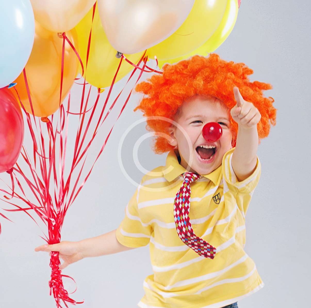 Small jumping boy holding bunch of balloons